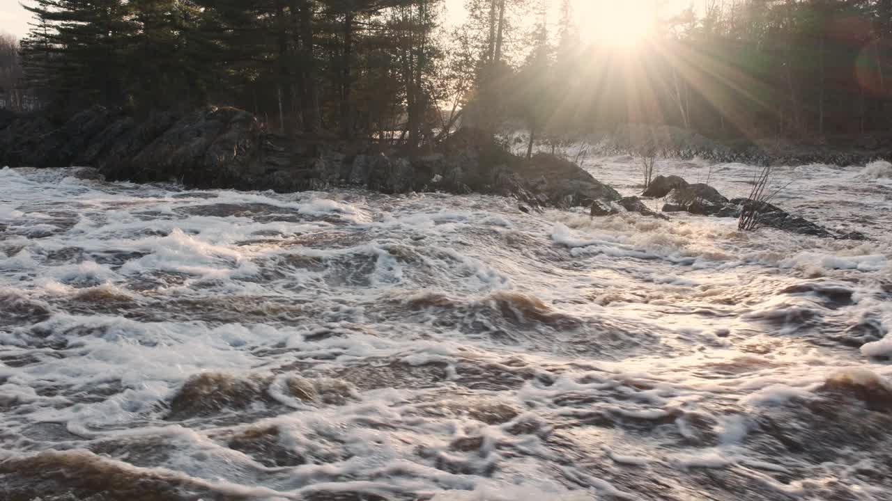 阳光把温暖的光芒洒在潺潺的河水上，河水里涌动着春雪视频素材