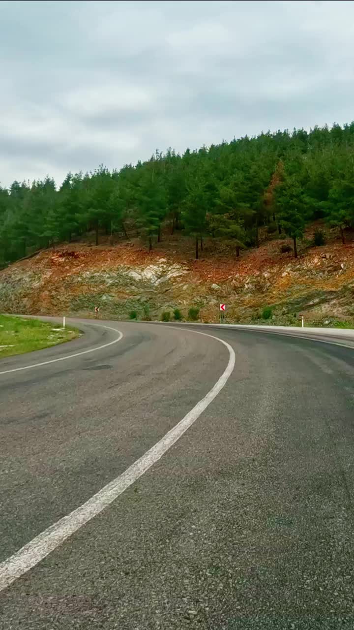 第一人称视频在山路上，开车通过狭窄的通道。视频显示了沿着山路的旅程。相机捕捉到山路上的风景视频素材