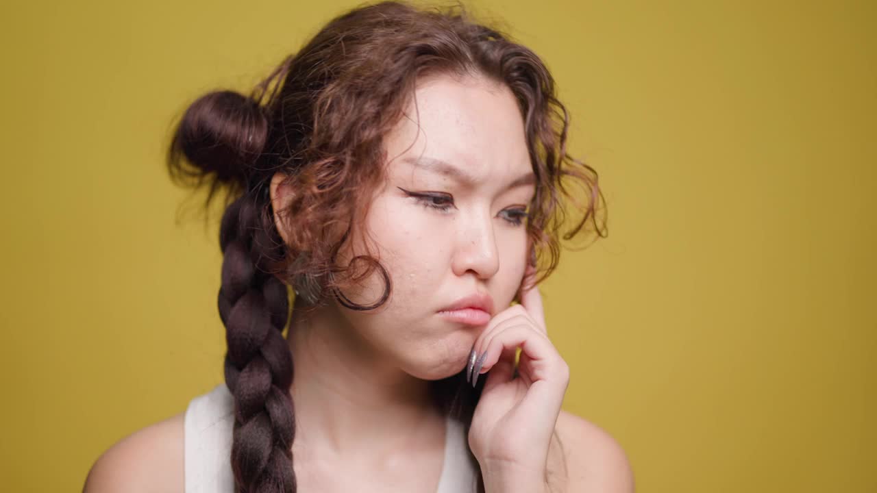 年轻的哈萨克女子，在黄色背景下，泪眼婆娑，表情悲伤视频素材