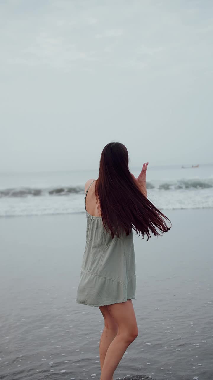 黑发长发的女孩在海边，垂直录像视频素材