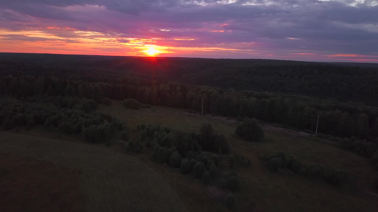 从鸟瞰图中可以看到这座城市的美丽景色。夹。夕阳下的紫色天空和绿树环绕的绿色田野。视频素材