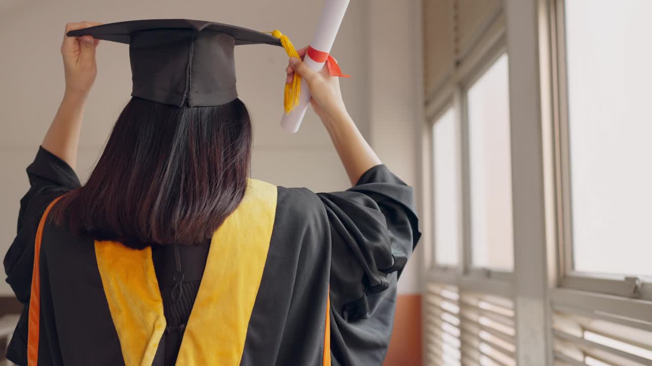 一个穿着毕业礼服拿着毕业证书的女人视频素材