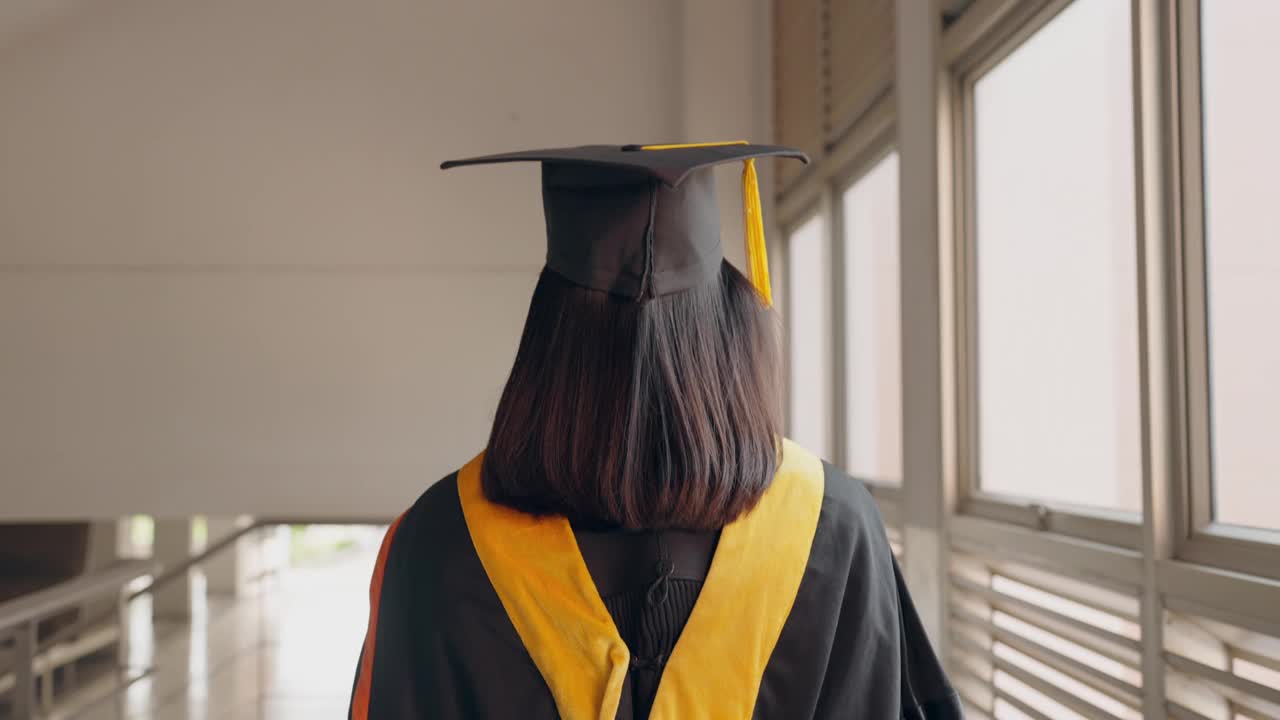 一个穿着毕业礼服的女人正走过走廊视频素材