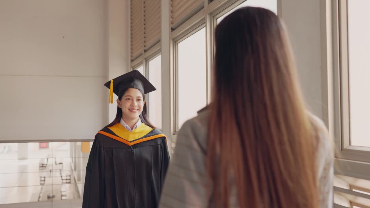 一个穿着毕业礼服的女人站在一个微笑的女人面前视频素材