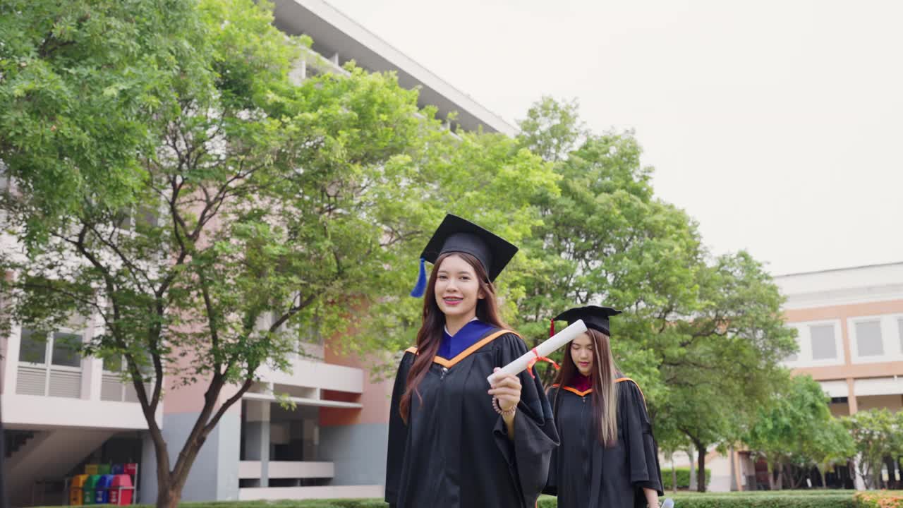 两个穿着毕业礼服的女人走在一栋大楼前视频素材