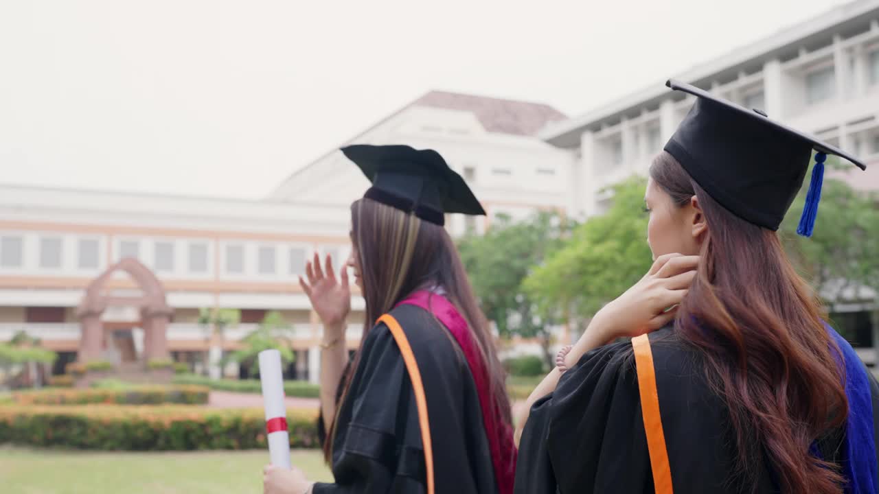 两个穿着毕业礼服的女人走在草地上视频素材