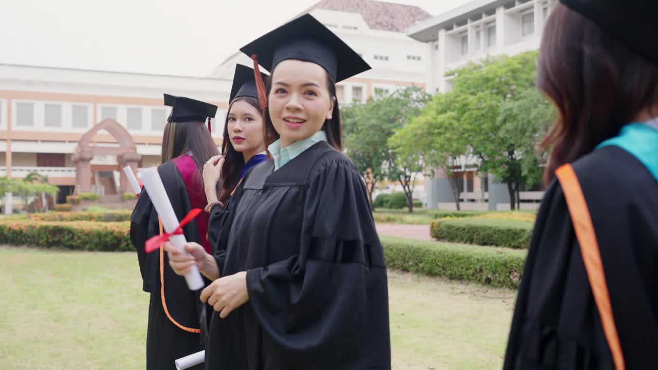 一群穿着毕业礼服的女生面带微笑，手里拿着毕业证书视频素材