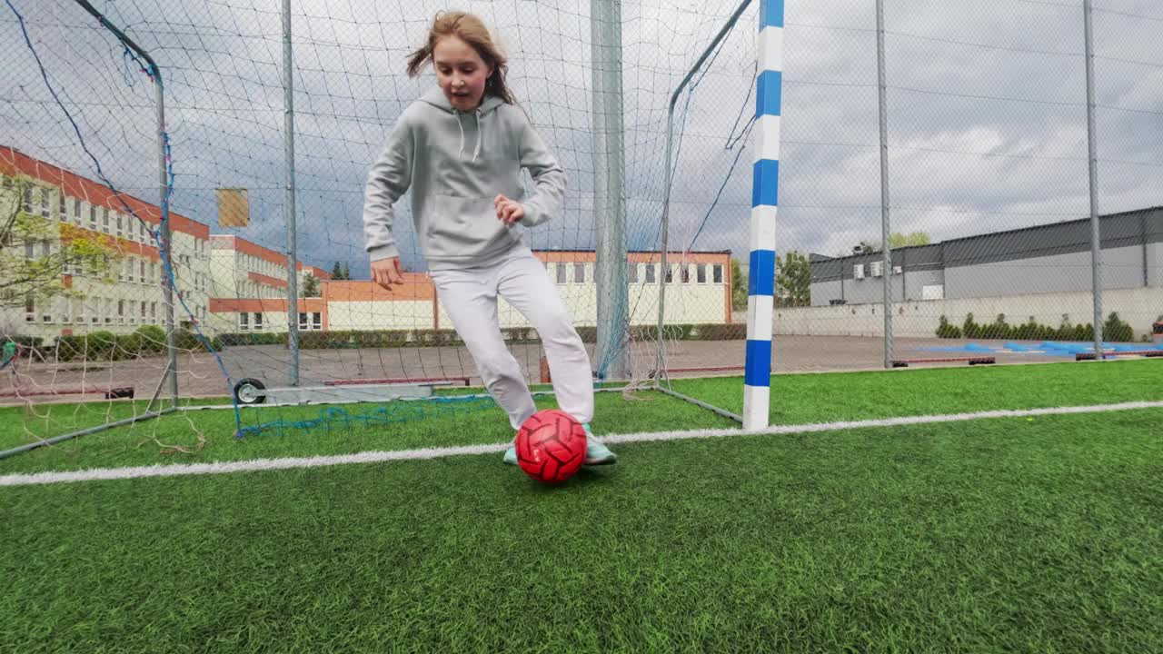 小女孩在足球场上用慢动作训练足球视频素材