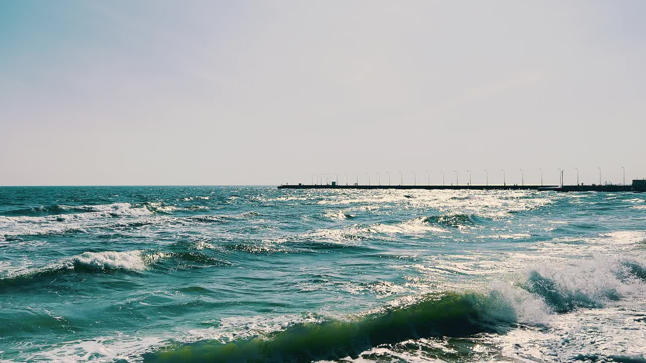 阳光下的海浪在海岸码头附近撞击视频下载