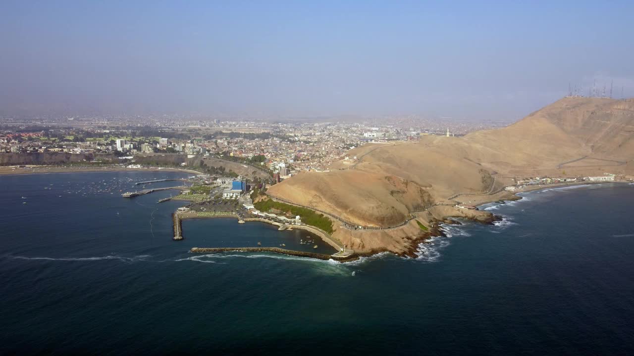 从沿海城市利马的海边鸟瞰图，在一个阳光明媚的日子里，天空雾蒙蒙的视频素材