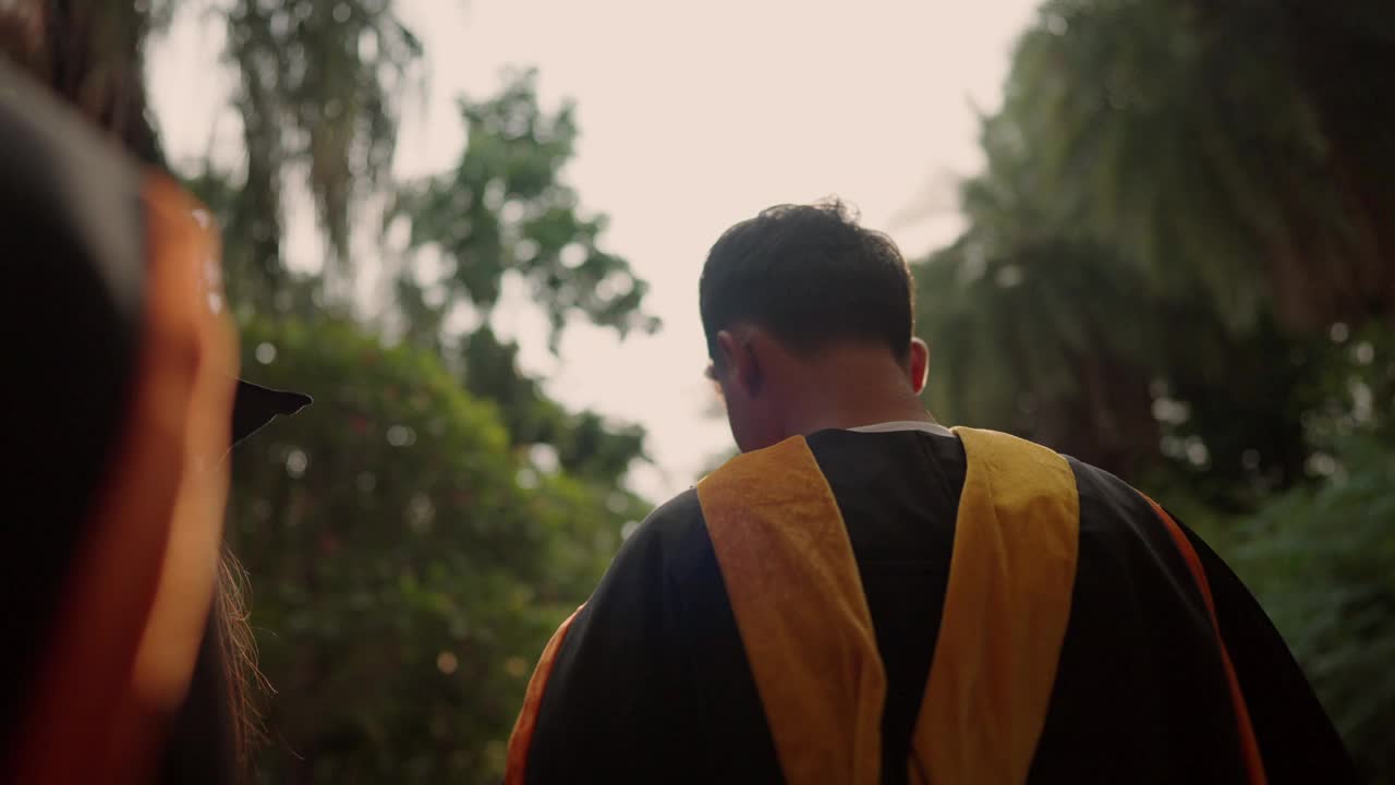 一个穿着黑黄相间的毕业袍的男人穿过森林视频下载