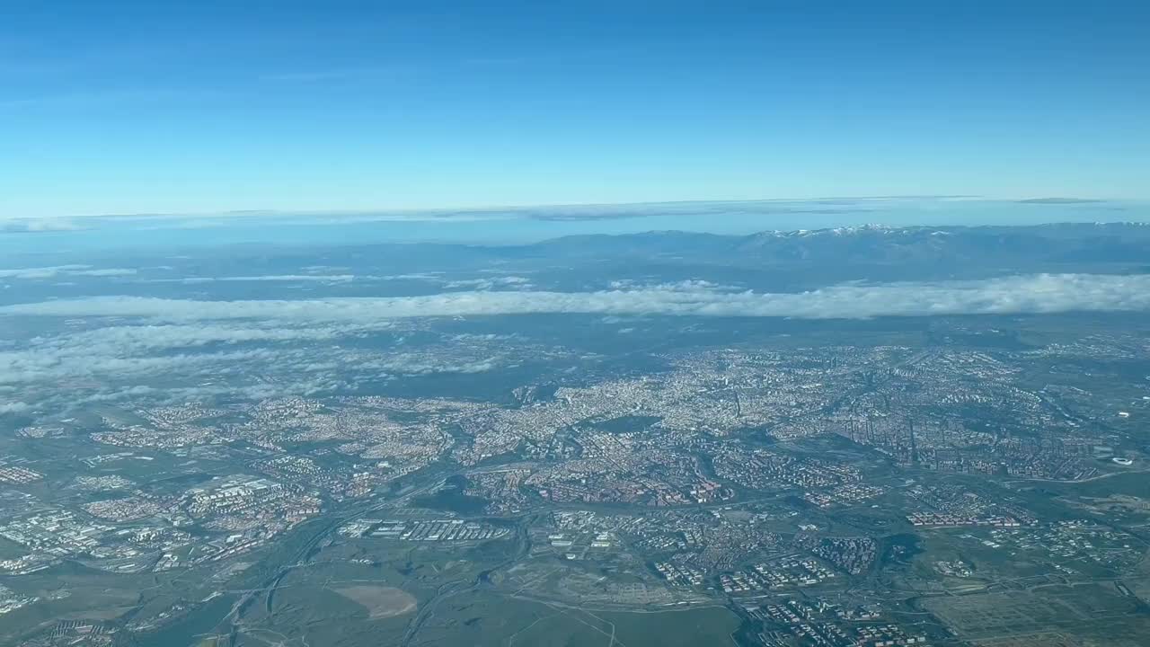 从西班牙马德里市的喷气式飞机驾驶舱鸟瞰图，从机场出发，天空中有一些云和雪山。4 k视频素材