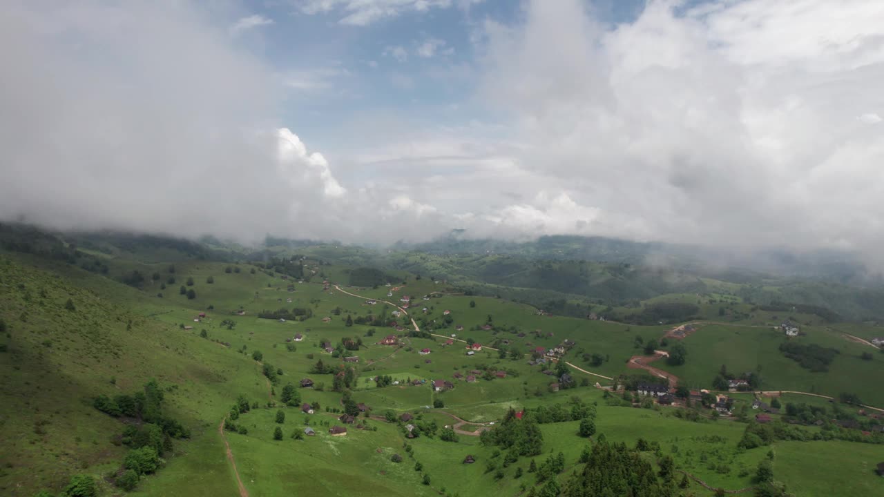 在多云的天空下，散落在青山之间的村庄，唤起了宁静的乡村景观，鸟瞰视频素材