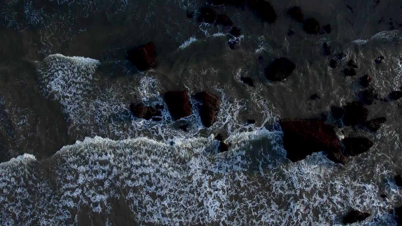 海滩海浪撞击岩石的鸟瞰图视频下载