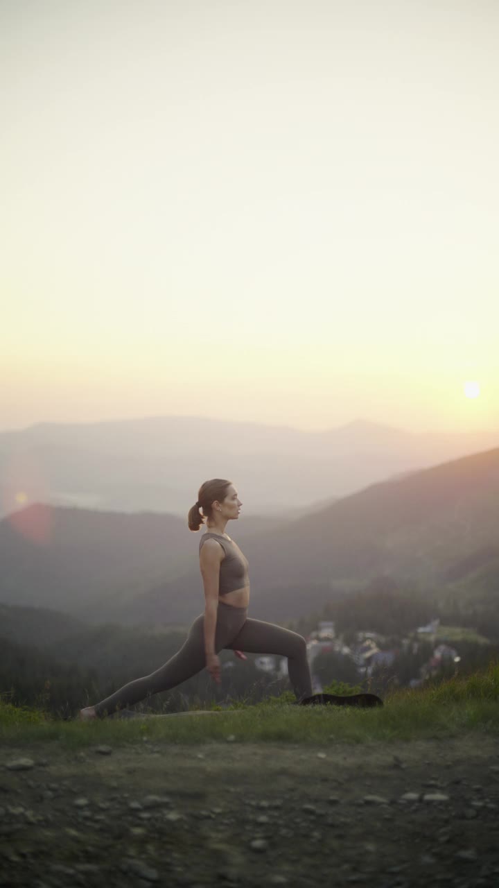 黄昏时分练习瑜伽的女人，与宁静的山景和谐相处。视频素材