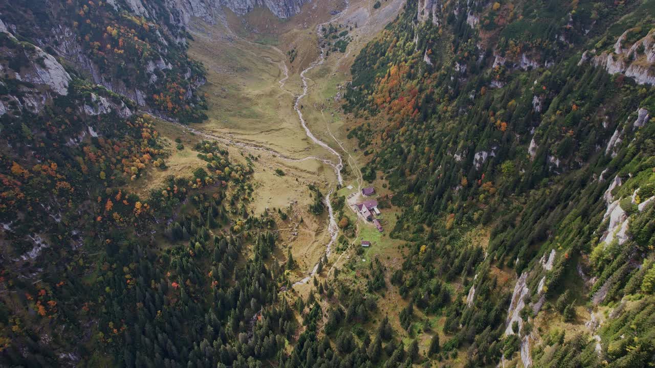 秋天的颜色笼罩着buegi山脉与Malaiesti小屋坐落在山谷中，鸟瞰视频素材