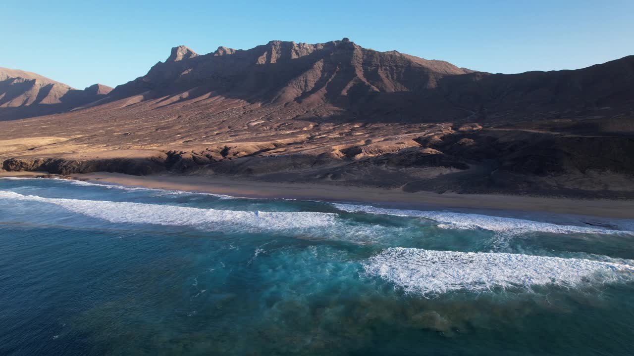 雄伟的宁静:海滩和山脉的空中舞蹈视频素材