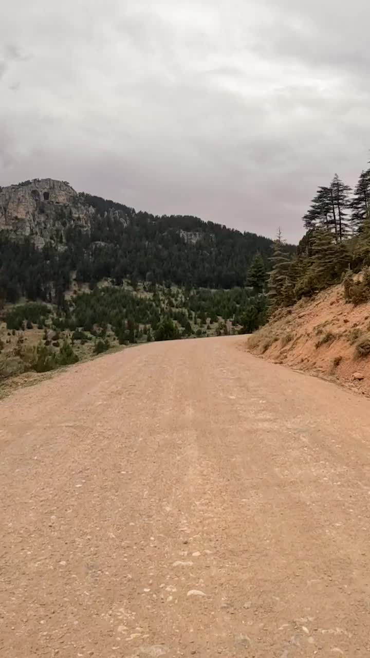 以风景如画的山为背景，沿着蜿蜒的土路，踏上一段宁静的风景之旅视频素材