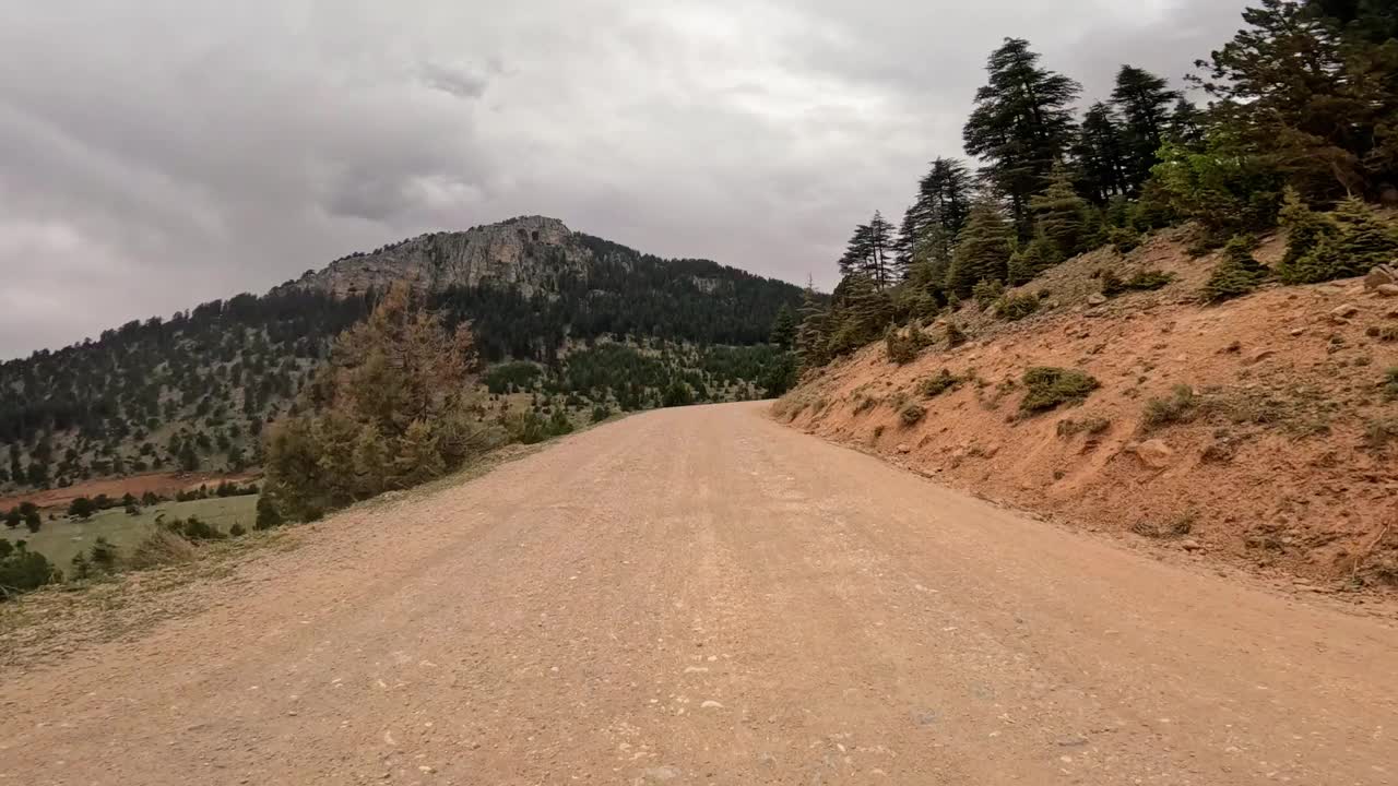 以风景如画的山为背景，沿着蜿蜒的土路，踏上一段宁静的风景之旅视频素材