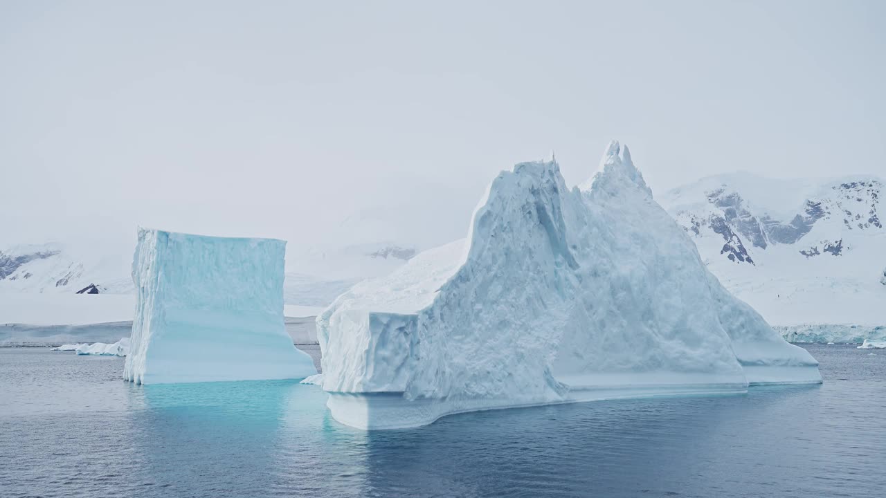 巨大的冰山冰形成在海上，漂浮在南极海洋海水在美丽的南极半岛冬季风光，惊人的自然在沿海海岸的巨大巨大的冰山场景视频素材