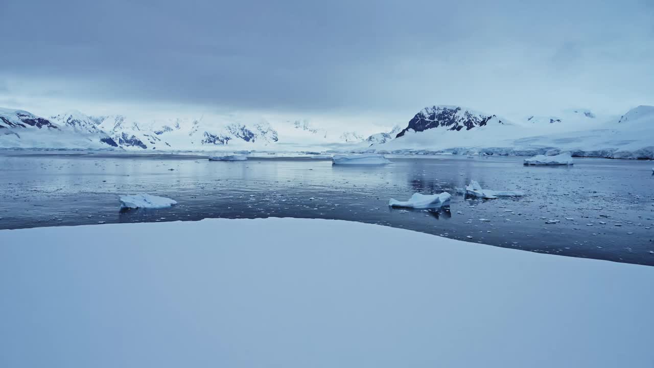 冬季景观与冰雪海洋和山脉在南极洲，冰山在美丽的戏剧性的黑暗忧郁的蓝色海岸海景在南极半岛海岸，冰冷的冬季海洋场景与冰视频素材