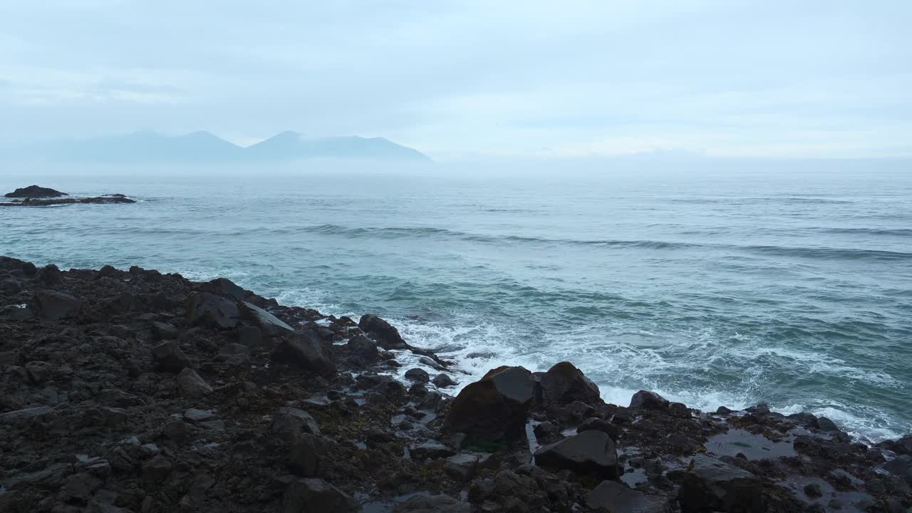 海岩石与移动的波浪在背景多云的地平线。夹。在阴天的海边，岩石突出在水面上。阴天里美丽的海景和岩石视频下载