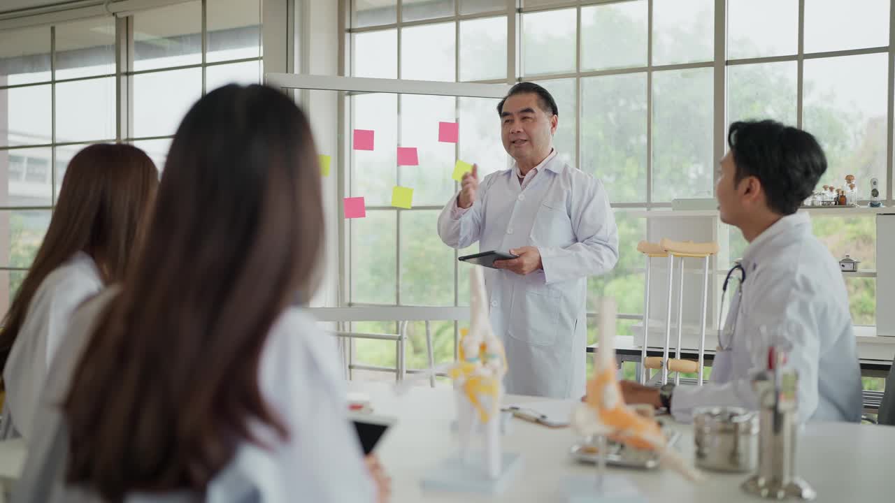 专业的亚洲中年医生进行医学教学，并在医学院的课堂上给医科学生讲课。医学生的听力与医学教育视频下载