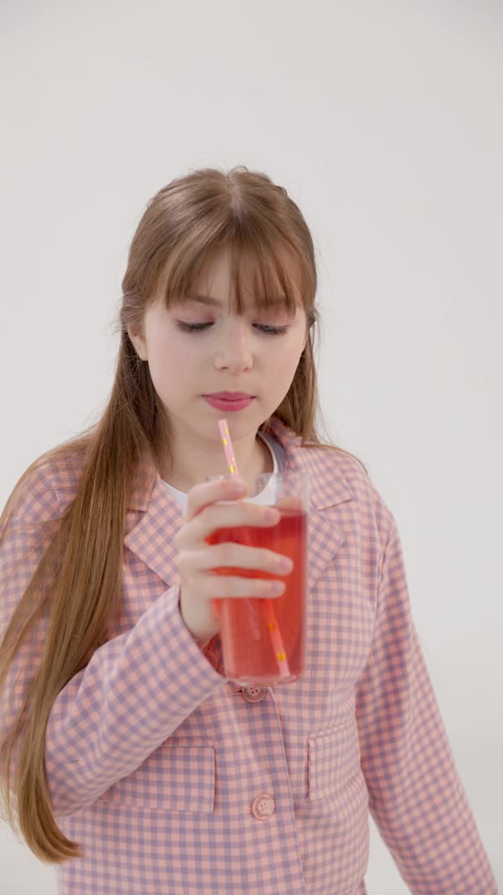 垂直视频。一个漂亮的少女用吸管吸草莓汁。视频下载