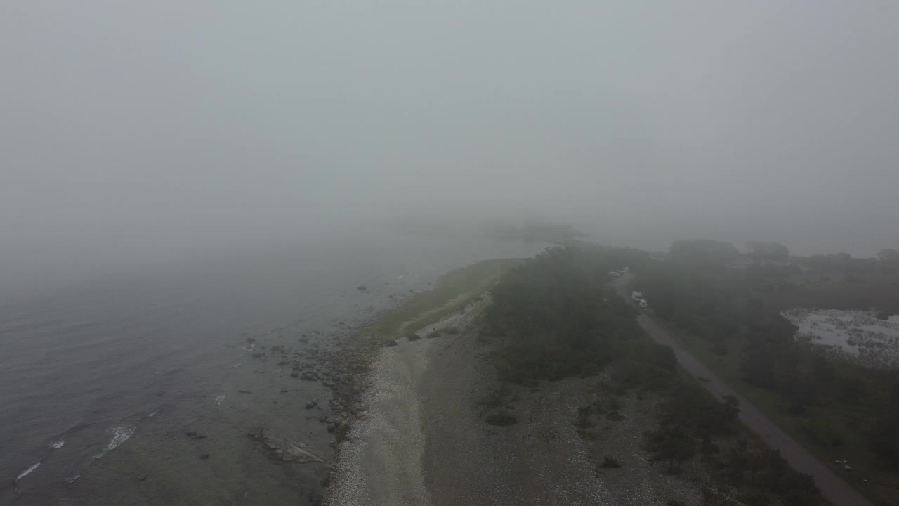 一个雾蒙蒙的早晨，瑞典奥兰德岛海岸线上的一条沿海公路的航拍画面视频素材