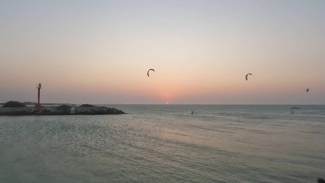 海边美丽的日落，有人在练习风筝板。视频下载