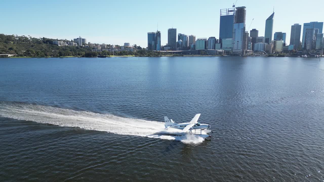 一架水上飞机优雅地沿着风景如画的天鹅河航行，背景是伊丽莎白码头。视频下载