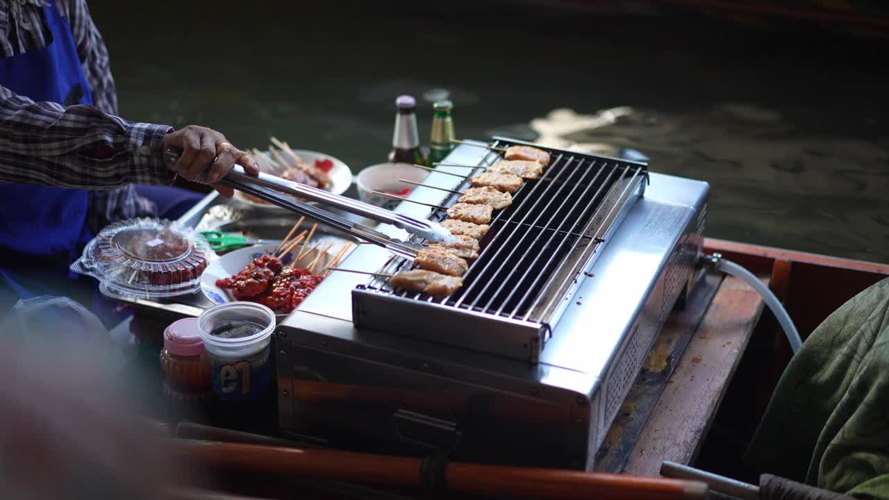 在离泰国曼谷不远的Damnoen Saduak水上市场，当地小贩正在烹饪传统的泰国食物视频素材