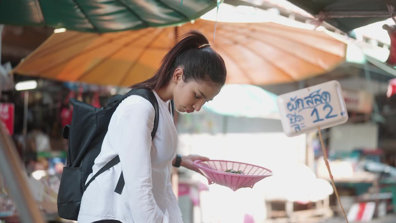 一名亚洲妇女在当地市场挑选蔬菜视频素材