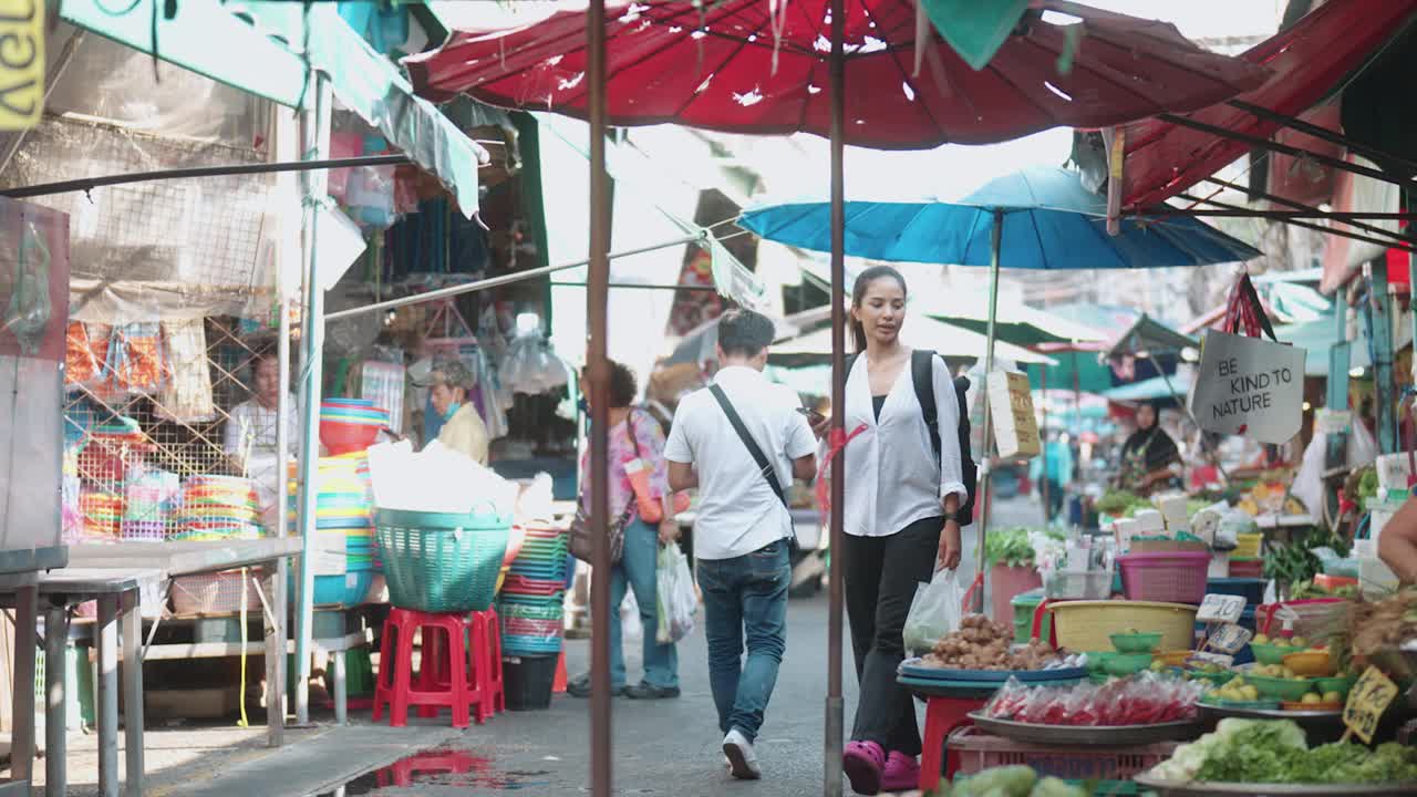 一名亚洲妇女在当地市场挑选蔬菜视频素材