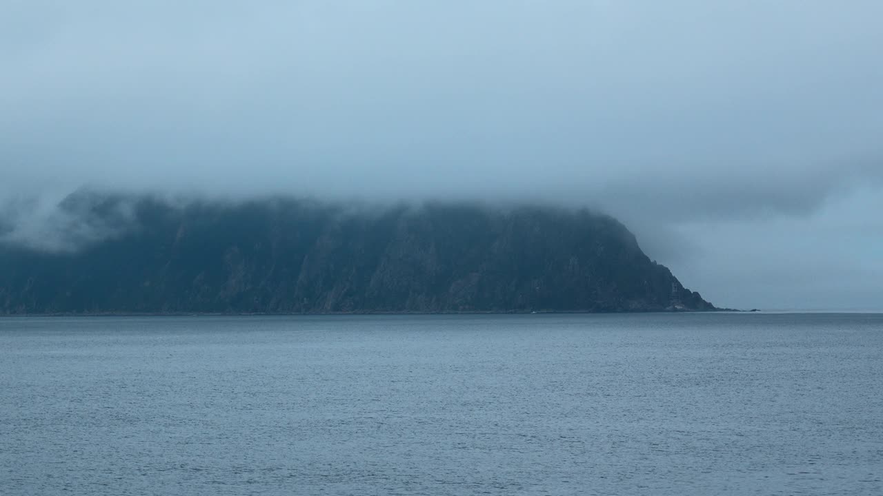 令人惊叹的岩石海景和低云。夹。在多云的天气里，蓝色的大海和深色的海岸岩石。电影般的海景，戏剧性的低云覆盖着海岸的悬崖视频素材