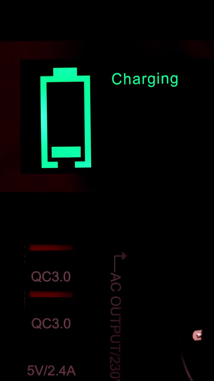 一个发光的绿色电池充电指示灯的垂直镜头。快速充电技术。视频下载
