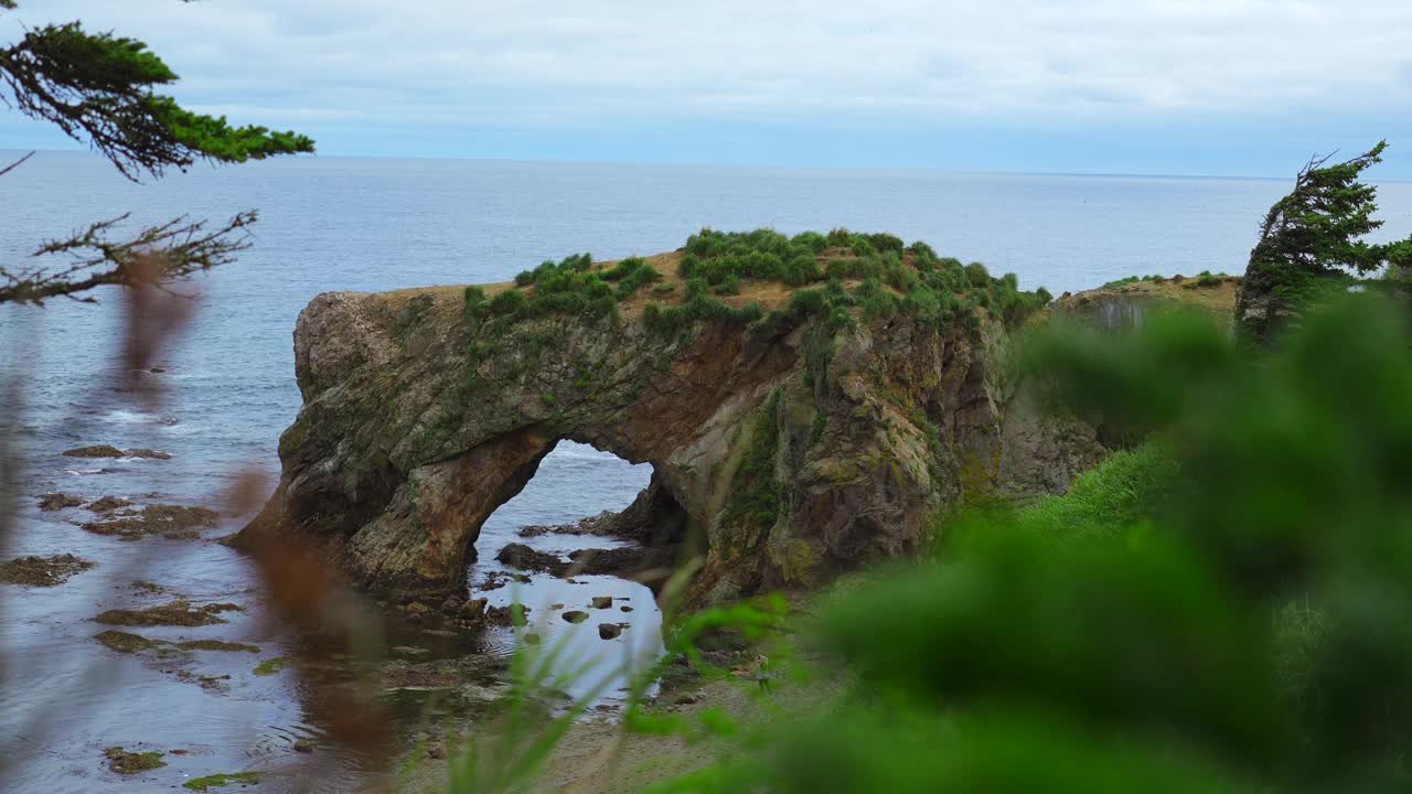 海边岩石上令人惊叹的拱门。夹。美丽的海景，岸边有石拱。在多云的夏日，岩石拱入大海的风景如画视频素材