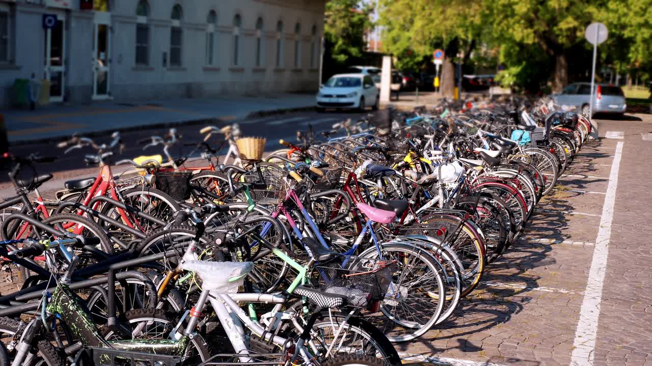 在阳光明媚的城市街道上停放拥挤的自行车:城市交通的快照视频素材