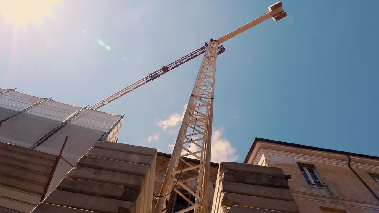 在湛蓝的天空下，雄伟的建筑起重机耸立在城市建筑工地上视频素材