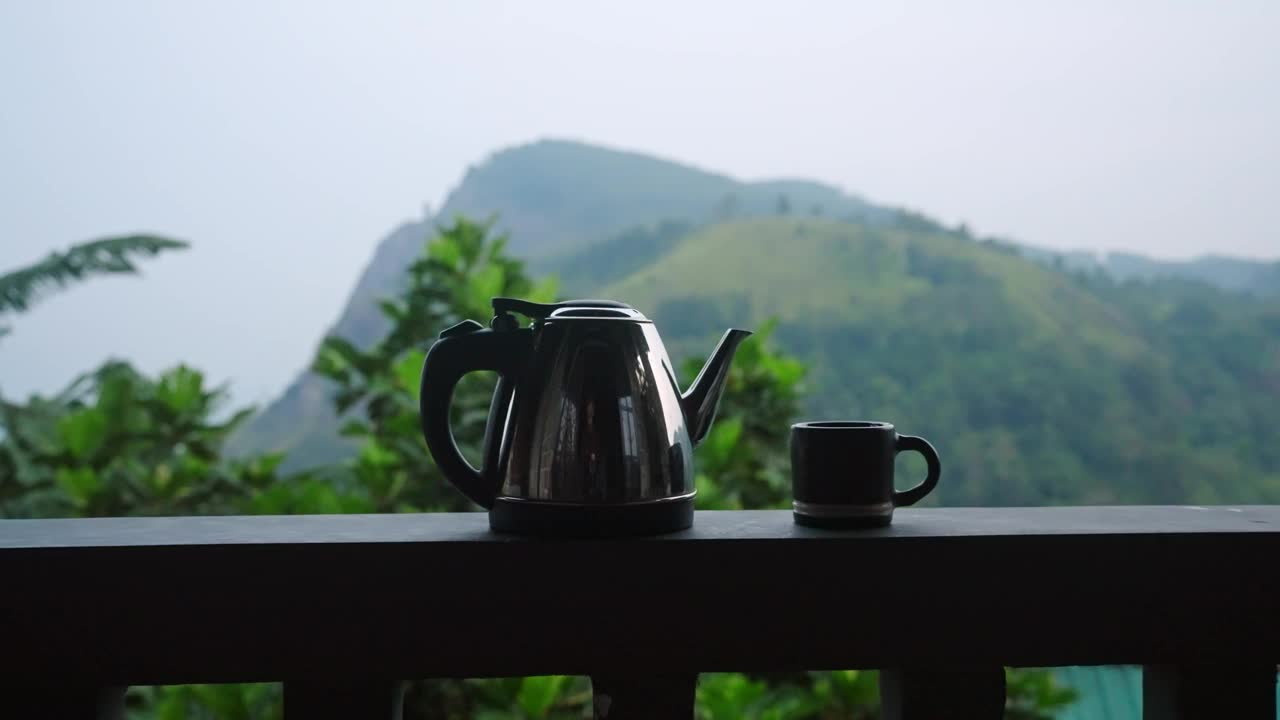 多莉拍摄的茶壶，杯子的栏杆上的豪华露台与山景，埃拉岩，斯里兰卡为背景。茶的体验，高端度假屋的自然风光，宁静的种植园景观。视频素材