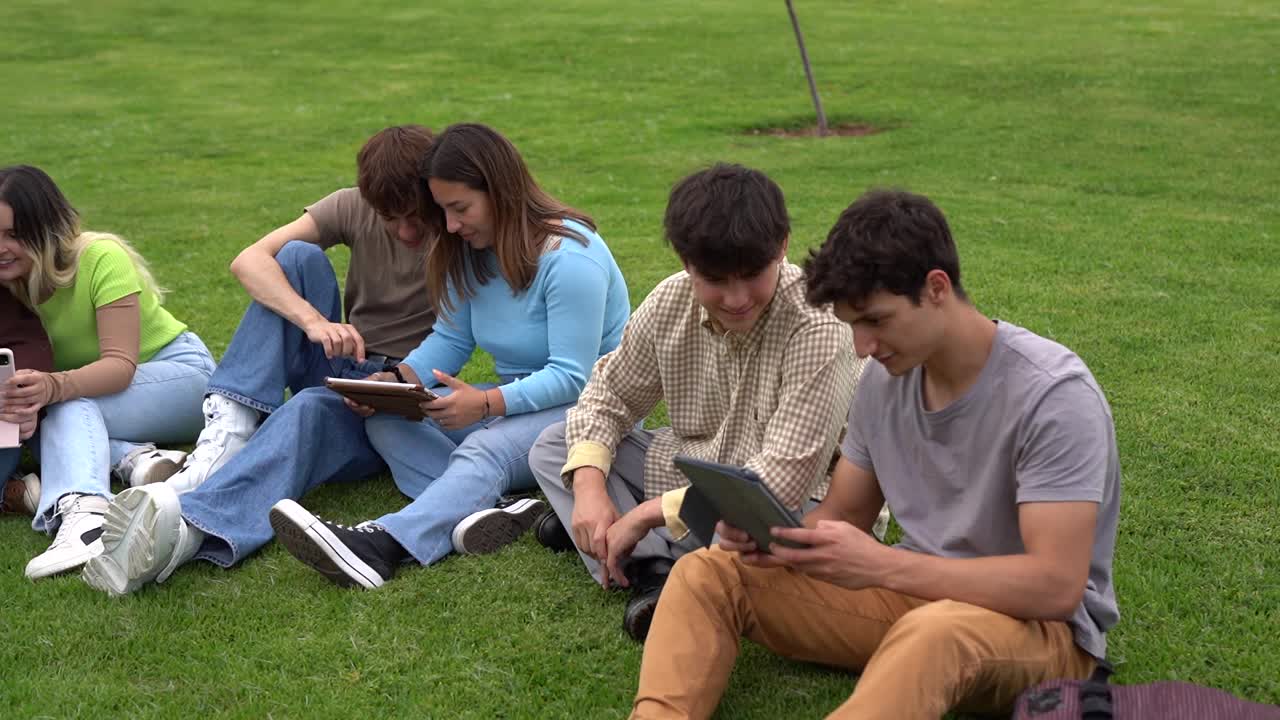 春天，不同的年轻学生坐在大学大楼外的草地上一起学习——学校和教育理念视频下载