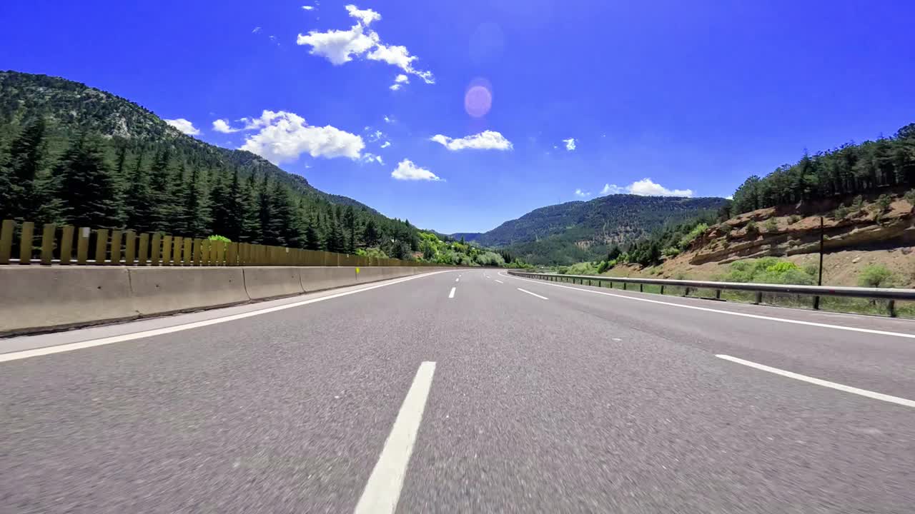 一条高速公路的壮丽景色穿过茂密的森林，背景是高耸的山脉，捕捉到风景优美的本质视频素材