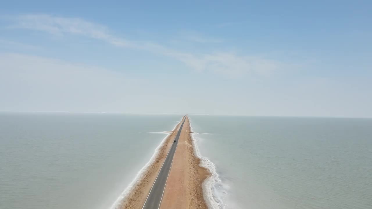 在古吉拉特邦通往天堂的道路上，一辆自行车在海洋中央骑行的航拍无人机镜头视频素材