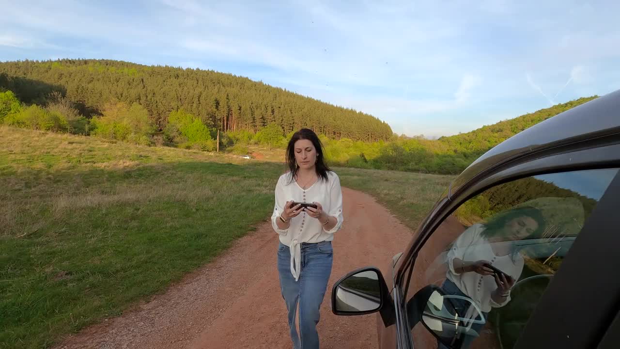 一名女子在未铺设的道路上迷路了，她正在使用手机上的导航应用程序。她使用移动GPS地图。视频素材