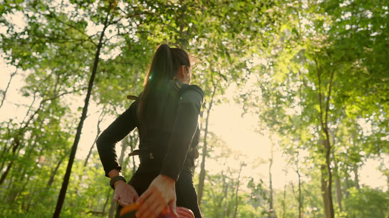 一个女人走在森林里，手里拿着一个粉红色和橙色相间的东西视频下载