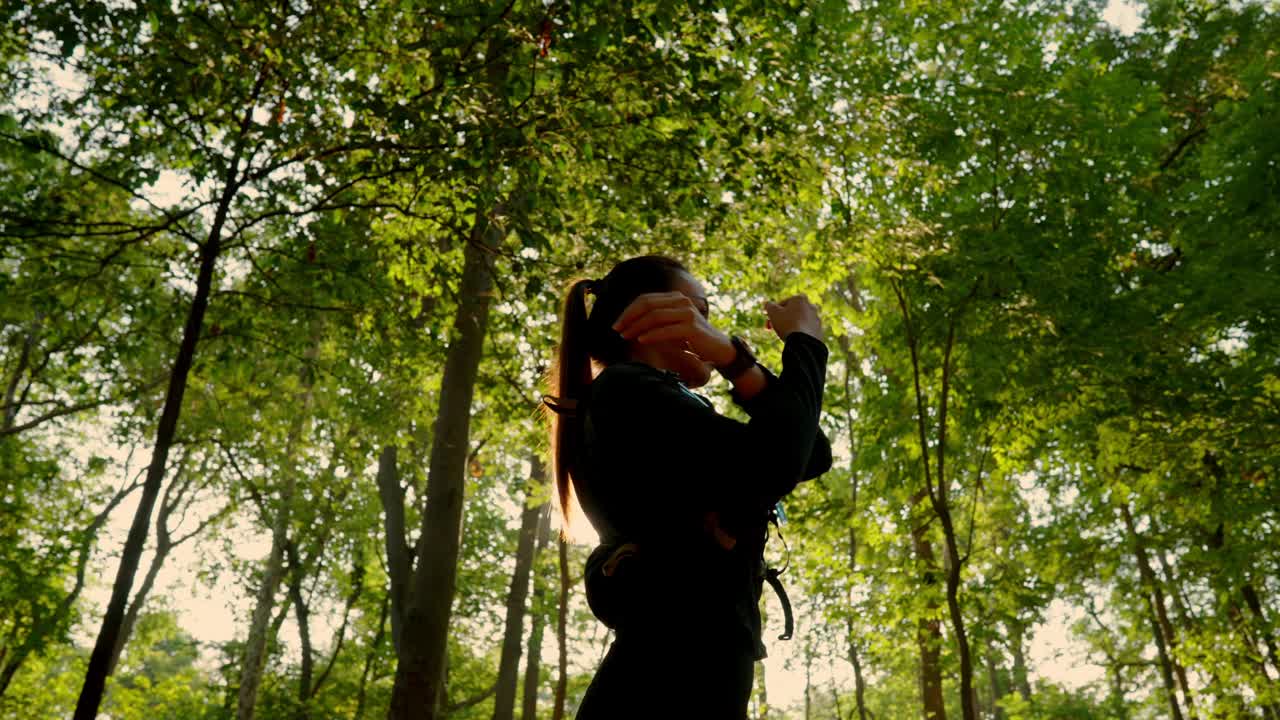一个女人站在森林里，穿着黑色的衣服，举起拳头视频下载