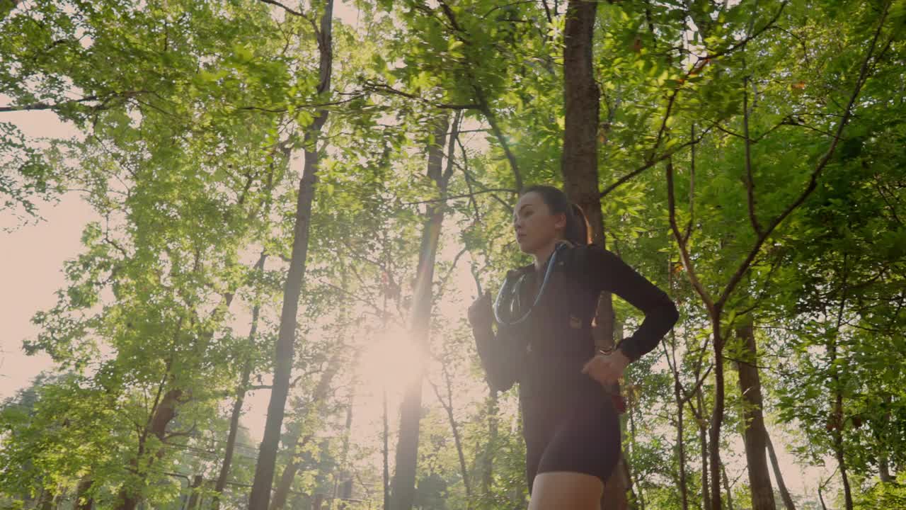 一个女人正跑着穿过森林，阳光照在她身上视频下载
