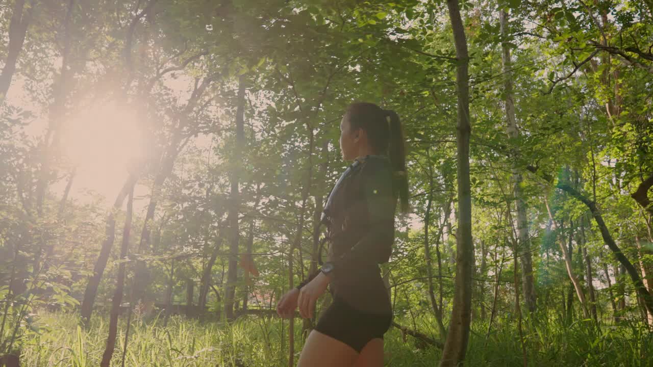 一个女人正穿过森林，阳光照在她身上视频下载