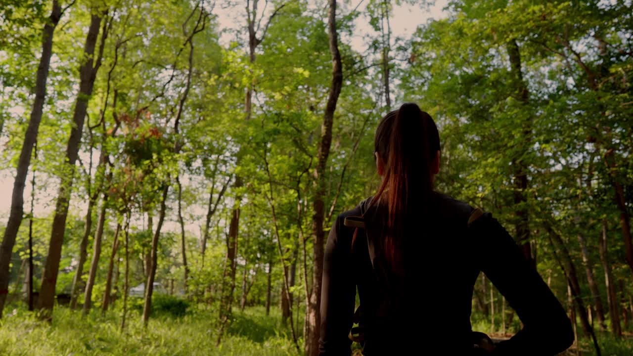 一个女人扎着马尾辫穿过森林视频下载