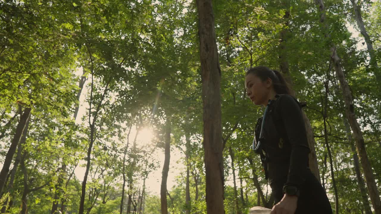 一个女人正穿过森林，阳光照在她身上视频下载